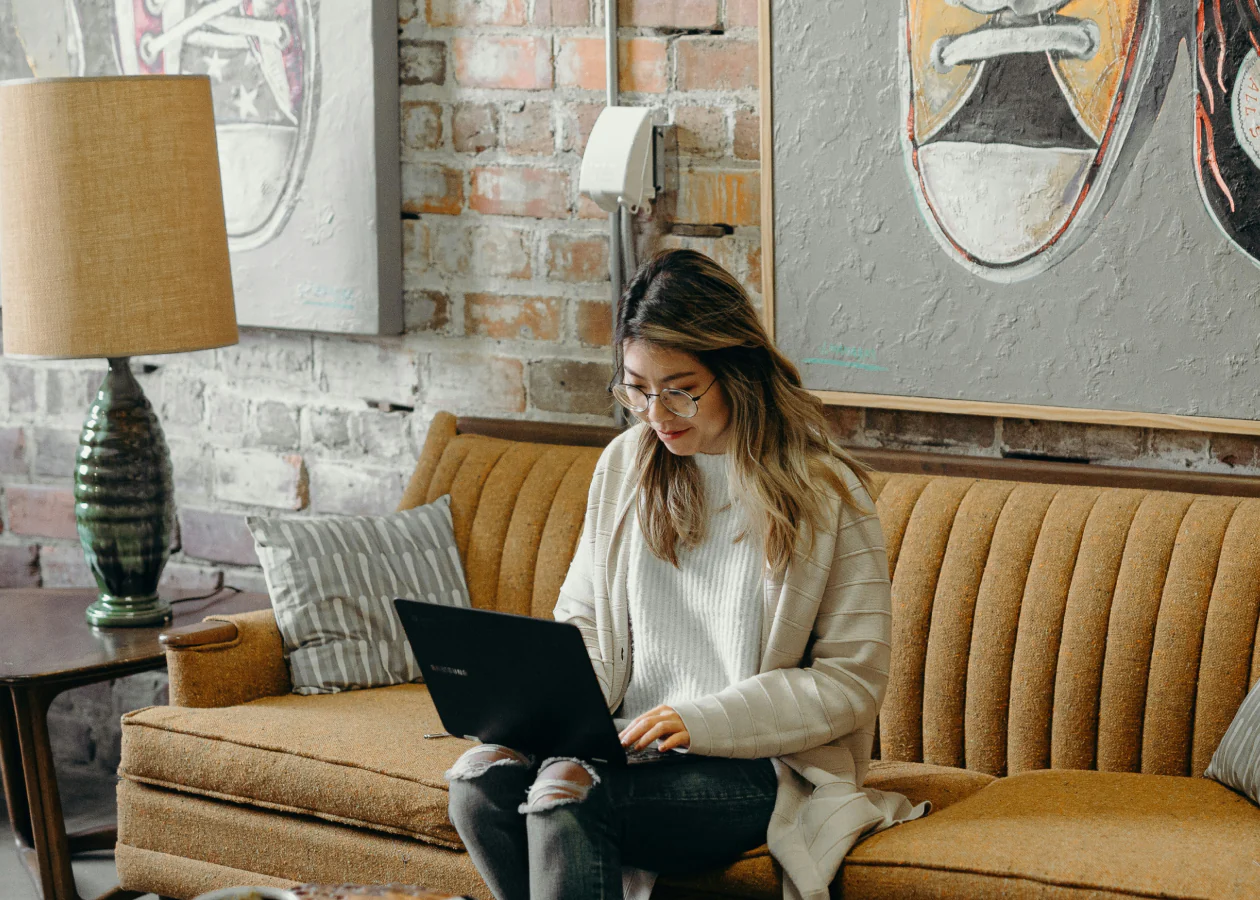 a woman with a computer and glases in a sofa
